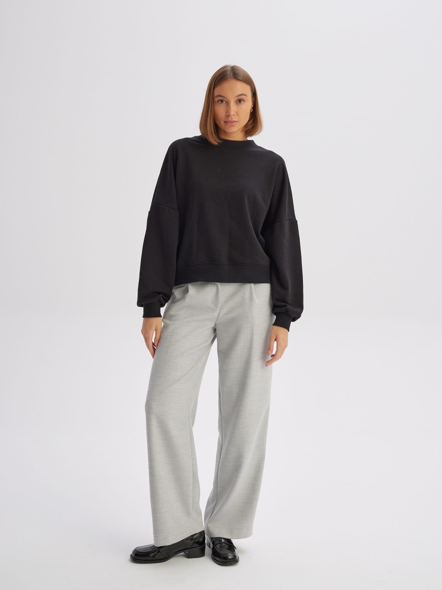 Krótka bluza damska CHILL O-NECK z przodu w pełnej sylwetce, czarna, z okrągłym dekoltem, oversize'owym fasonem i miękką bawełnianą dzianiną marki MAFFEI.